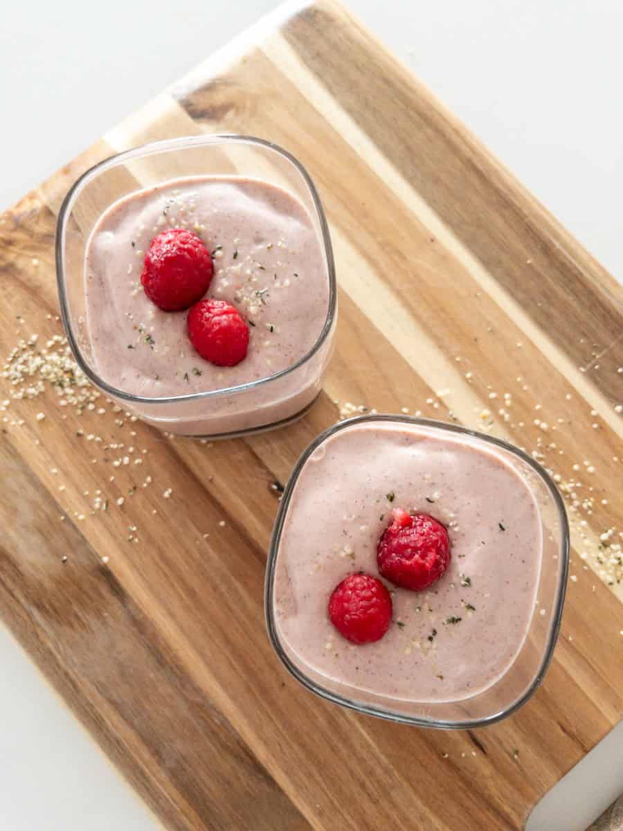 Raspberry hemp almond butter smoothie in two glasses with raspberries on top