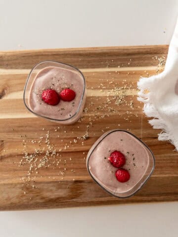 raspberry hemp almond butter smoothie on cutting board, adorned with hemp hearts